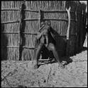 Man sitting next to a fence and holding a baby