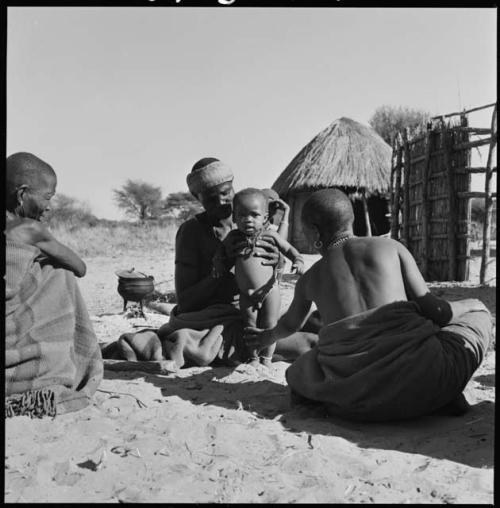 Three women sitting, one is holding a baby