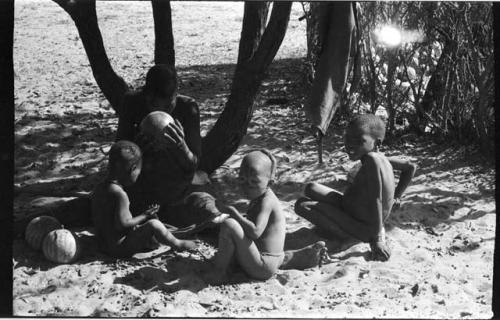 Adults and children sitting under tree