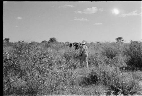 Expedition team walking in grass, seen from behind