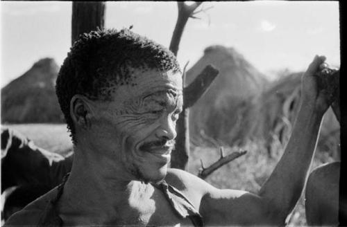 Man standing with his hand on a tree, close-up