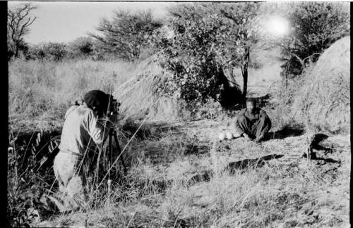 John Marshall photographing /Gishay beside two ostrich shells