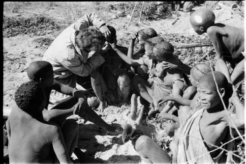 Elizabeth Marshall Thomas putting ointment in Oukwane's eyes; the group watching