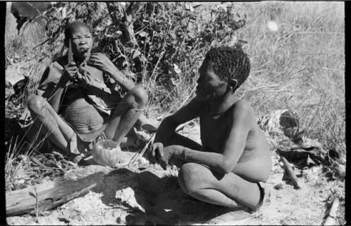 /Twikwe cutting meat at her lips with a knife, Oukwane in the foreground