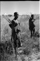 Oukwane and !Gai standing with their hunting equipment