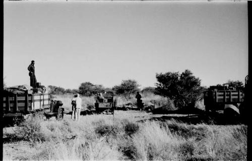 Expedition trucks in a group, expedition members standing around