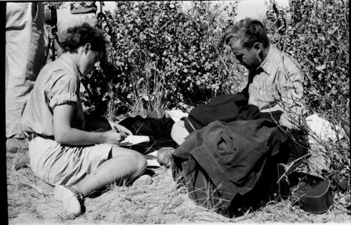 Elizabeth Marshall Thomas sitting and taking notes; another expedition member sitting