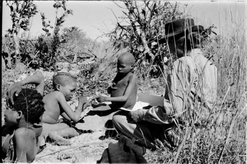 /Gaiamakwe and !Ou/ke playing a hand game; Lorna Marshall taking notes