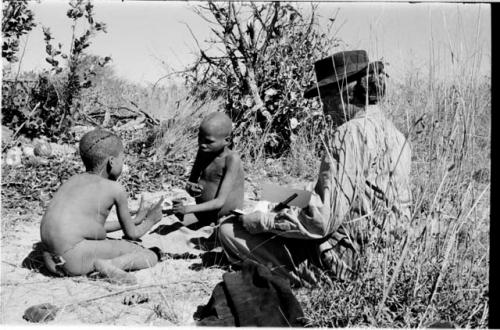 /Gaiamakwe and !Ou/ke playing a hand game; Lorna Marshall taking notes