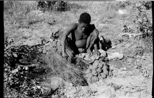 Oukwane squeezing the stomach contents of gemsbok using a grass sieve