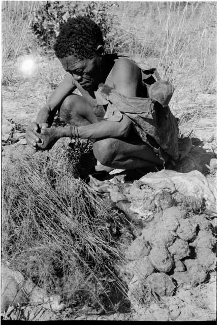 Oukwane squeezing the stomach contents of the gemsbok using grass sieve, close-up