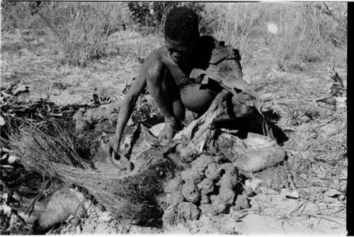 Oukwane scooping liquid out of hollow in the ground to pour into empty gemsbok stomach