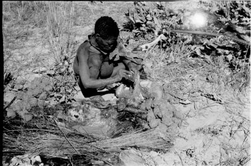 Oukwane scooping liquid out of hollow in the ground to pour into empty gemsbok stomach