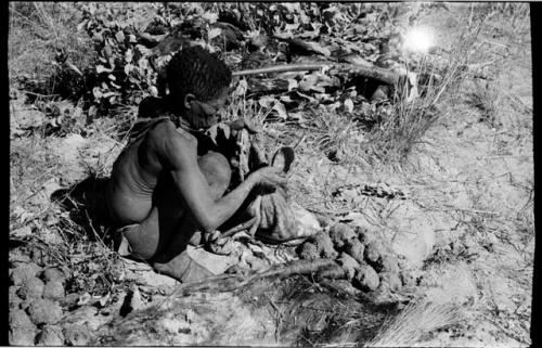 Oukwane scooping liquid out of hollow in the ground to pour into empty gemsbok stomach