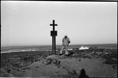 Man standing next to monument on beach