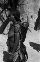 Woman carrying a baby on her back, with baobab tree in background