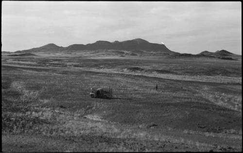 People standing near truck, with hills in background