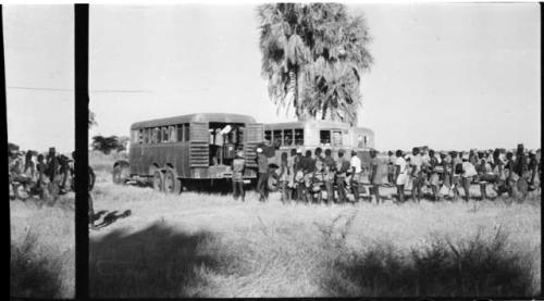 Large group of people standing in line next to trucks