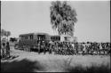 Large group of people standing in line next to trucks