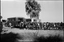 Large group of people standing in line next to trucks