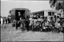 Large group of people standing in line next to trucks