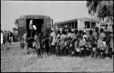 Large group of people standing in line next to trucks