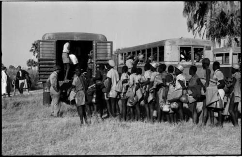 Large group of people standing in line next to trucks