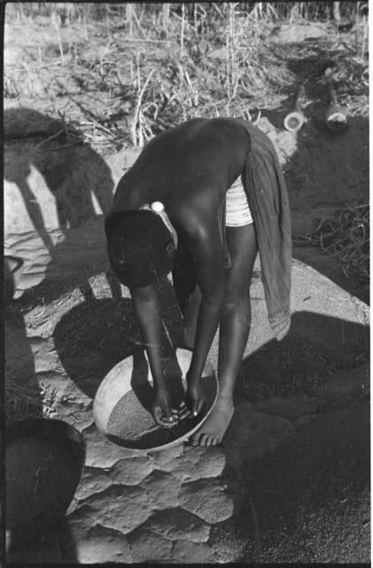 Woman leaning over a basket of grain