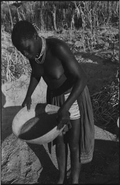 Woman standing and holding a basket of grain