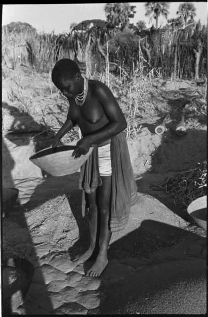 Woman standing and holding a basket of grain