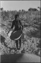 Woman standing and holding a basket of grain