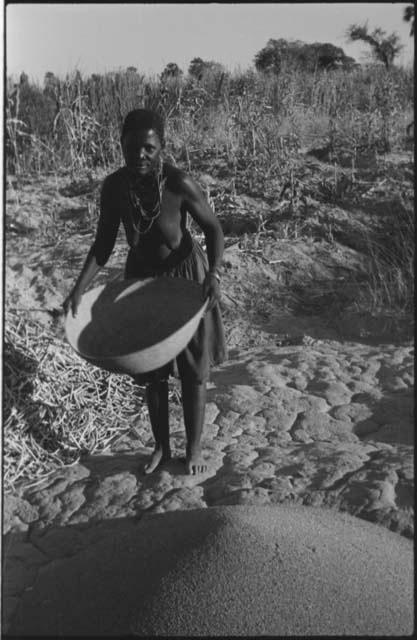 Woman standing and holding a basket of grain