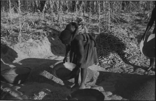 Woman carrying a baby on her back and holding a basket of grain