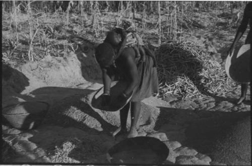 Woman carrying a baby on her back and holding a basket of grain