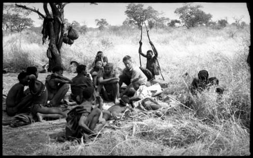 Group of people including "/Qui Hunter" lying down, ≠Toma, John Marshall, and !Kham holding sticks as crutches