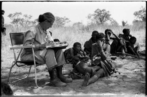 Lorna Marshall taking notes, !U, !Ungka Norna, /Naoka ("Gao Medicine's" first wife), and other unidentified people in the background