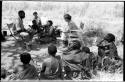 Group of people including Lorna Marshall and Kernel Ledimo seated in chairs, !U and !Ungka Norna seated between them, Elizabeth Marshall Thomas in the background, and other unidentified people