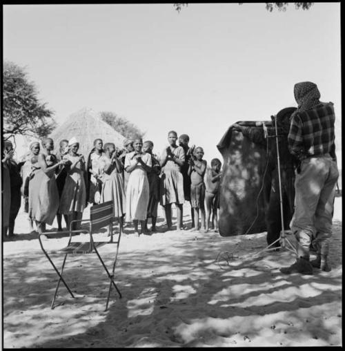 Group of women clapping and singing, being recorded with microphone