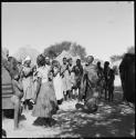 Women dancing in front of a group of women clapping and singing, being recorded