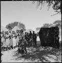 Women dancing in front of a group of women clapping and singing, being recorded