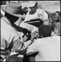 Group of people having their skin color documented, with Nicholas England taking notes