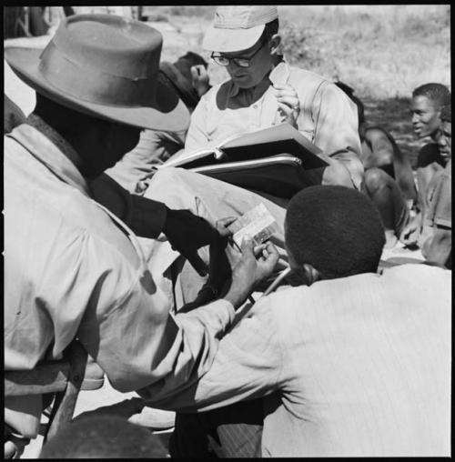 Group of people having their skin color documented, with Nicholas England taking notes