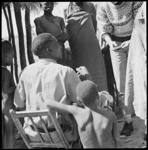 Kebuelemang sitting, and a group of people having their skin colors documented by Deborah Marshall