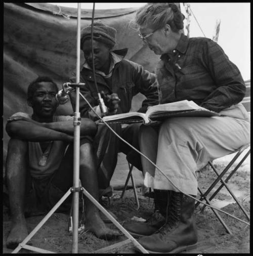 Man giving a word list at a microphone, with Kernel Ledimo and Lorna Marshall