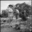 C. J. Mathias, Deborah Marshall and Lorna Marshall reading and writing at camp