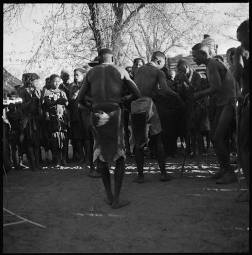 Group of women singing, and three men dancing