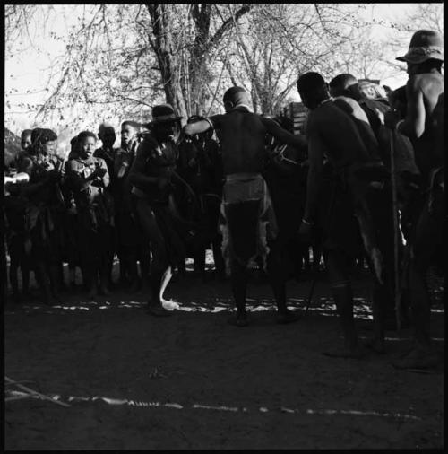 Group of women singing, and men dancing