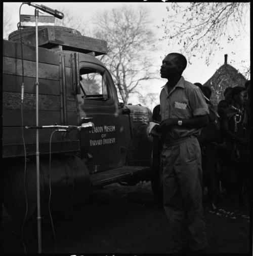 Group of people singing, with Kernel Ledimo announcing into microphone, next to expedition truck