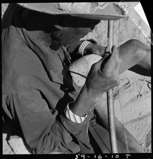 Kafuro playing the hunting bow, braced, with calabash, view over his right shoulder