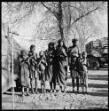 Group of women and children singing, with expedition truck in background